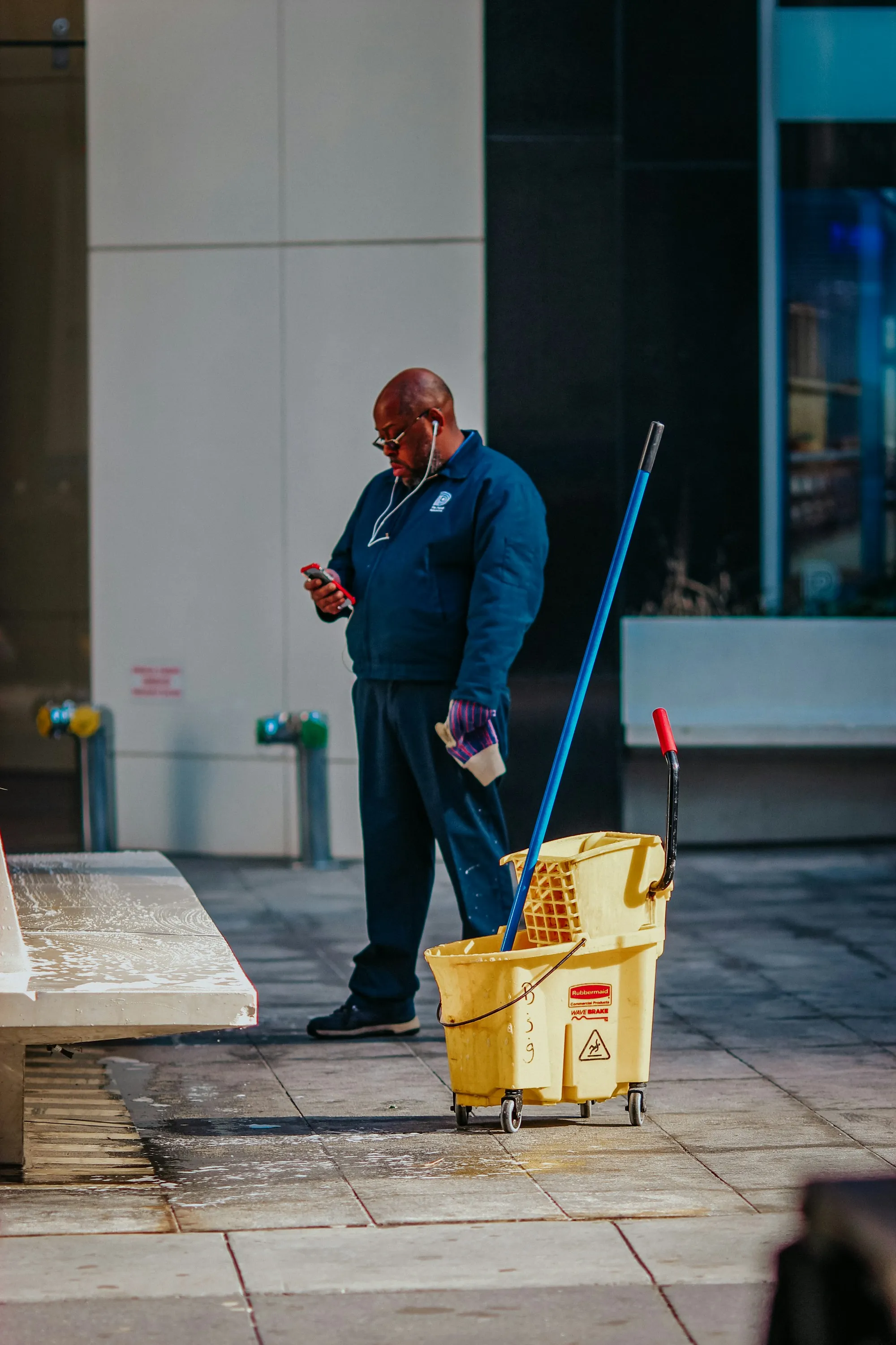 Janitor holding a mop beside a yellow bucket