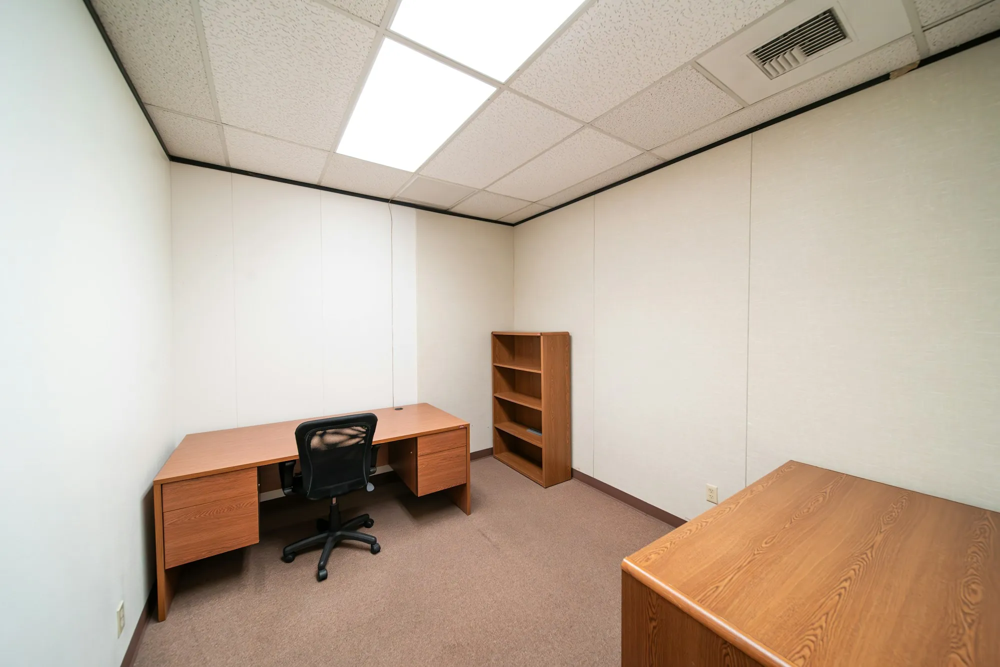 Small carpeted private office with a desk